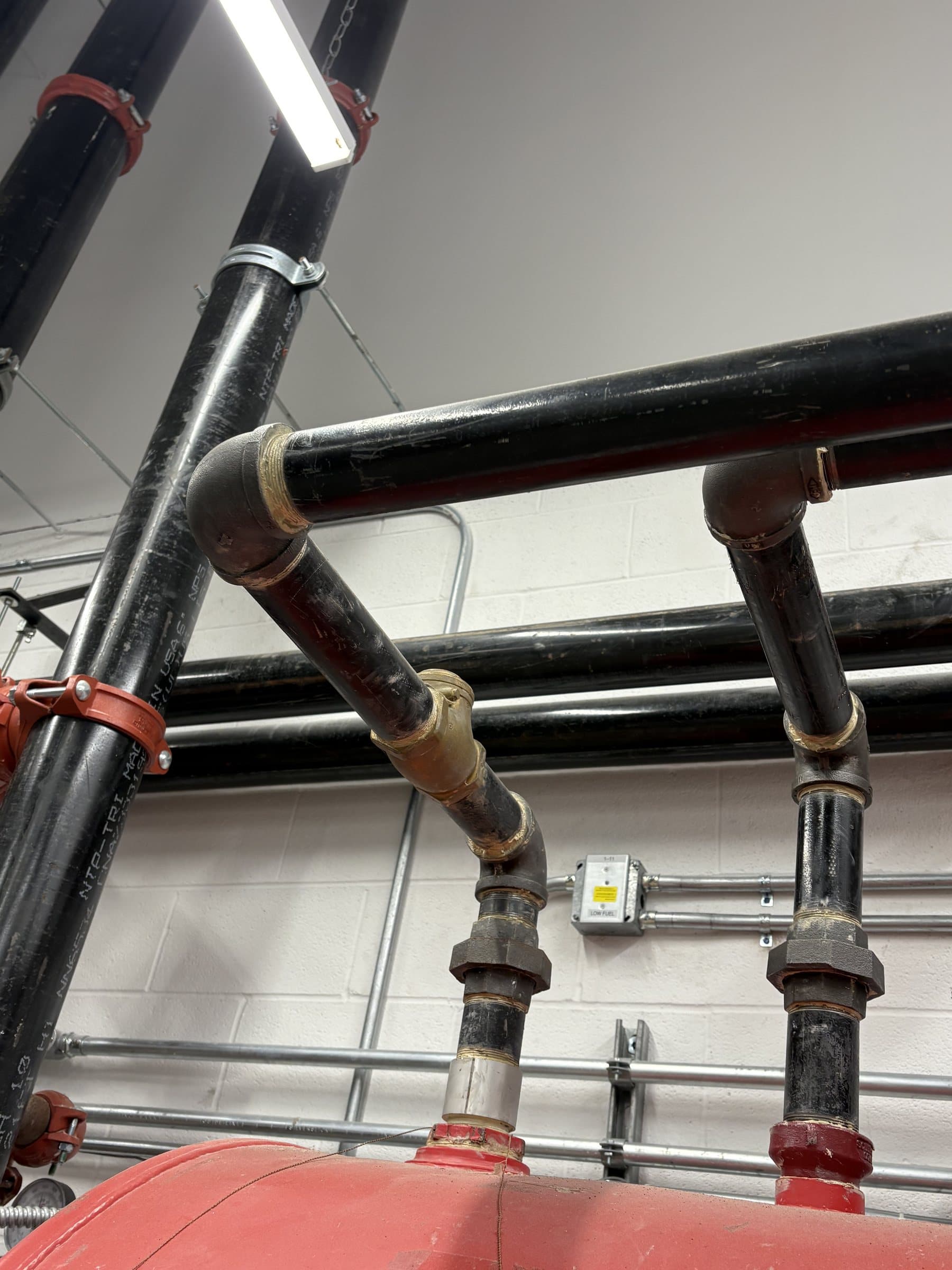 Fuel tank shoulder and overhead piping in an equipment room.
